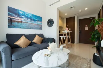 a living room with a blue couch and a table at Reva 1BR - Downtown Living with Burj Khalifa View in Dubai