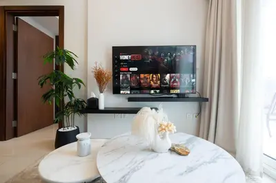 a living room with a table and a tv at Reva 1BR - Downtown Living with Burj Khalifa View in Dubai