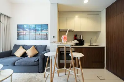 a living room with a blue couch and a kitchen at Reva 1BR - Downtown Living with Burj Khalifa View in Dubai