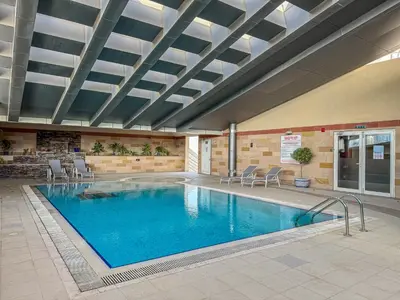 a large swimming pool in a building with chairs at Bright 1BR with Canal Views Near Burj Khalifa in Dubai