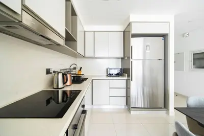 a kitchen with white cabinets and a stainless steel refrigerator at SettlerHomes - Sunrise Beach Bliss With Private Beach in Dubai