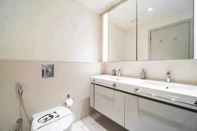 a bathroom with a toilet and a sink and a mirror at SettlerHomes - Sunrise Beach Bliss With Private Beach in Dubai