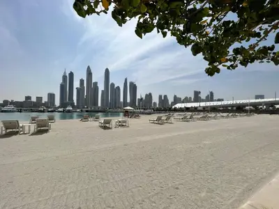 a beach with chairs and a city in the background at SettlerHomes - Sunrise Beach Bliss With Private Beach in Dubai