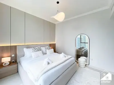 a white bedroom with a large bed and a mirror at Beachfront 1B at Palm Jumeirah with Balcony & Views in Dubai