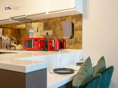 a kitchen with a counter with two blue chairs at Le Chateau Vacation Homes,Fashion Avenue Residence in Dubai