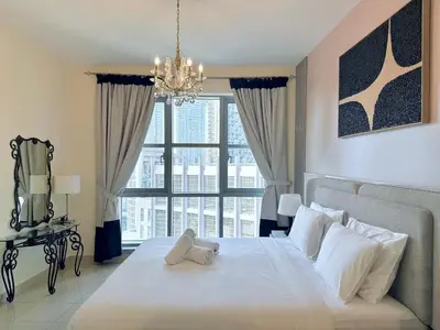 a bedroom with a large white bed with a chandelier at Urban Retreat 1BR with Pool & Burj Glimpse in Dubai
