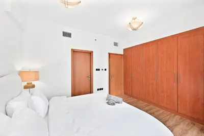 a bedroom with a white bed and wooden cabinets at Luxury 2BR Marina View-walking distance to JBR beach, marina mall & metro in Dubai
