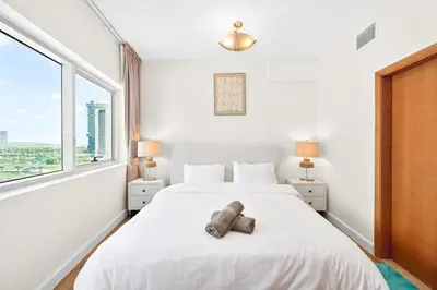 a white bedroom with a large bed and a window at Luxury 2BR Marina View-walking distance to JBR beach, marina mall & metro in Dubai
