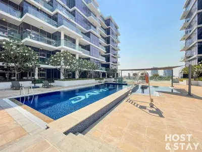 a swimming pool in front of a tall building at Modern Studio in Loreto 1A, Damac Hills in Dubai