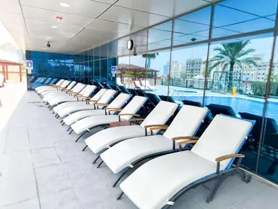 a row of white chairs next to a swimming pool at Luxuries Sky View Apartment in Dubai
