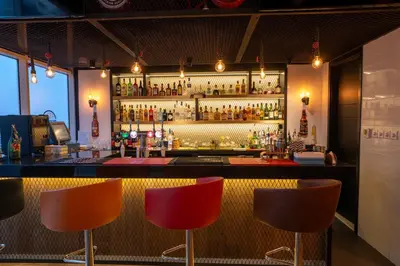 a bar with three chairs and a counter with liquor bottles at Hilton Garden inn Dubai Jumeirah in Dubai