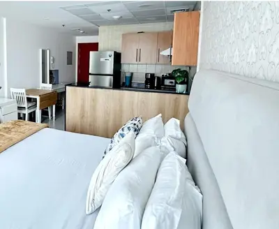 a bedroom with a white bed and a kitchen at MARINA VIEWs STUDIO APARTMENT in Dubai