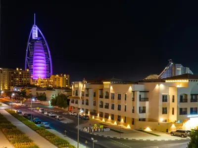 a city at night with a tall building with a clock tower at Modern Jumeirah Apartment Near Beach in Dubai
