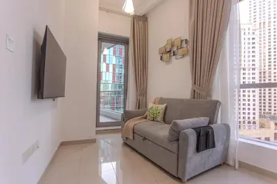 a living room with a couch and a tv at Stylish Studio Apartment with a Balcony Offering Sophistication, Spectacular Views & Beachside Living! in Dubai