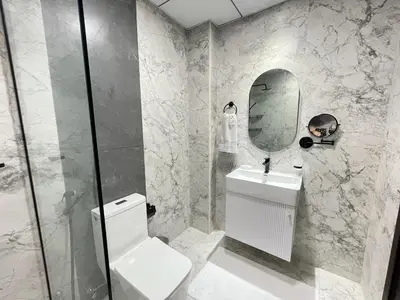 a white bathroom with a toilet and a mirror at Cosy Studio in Opalz by Danube, Al Barsha South in Dubai