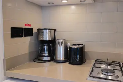 a kitchen counter with two coffeemakers and a stove at Cosy 1BR in Sobha Hartland in Dubai
