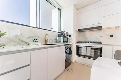 a kitchen with white cabinets and a window at Minutes from Circle Mall, Grocery Stores & Bus Stop 2BR with Mini Private Pool on Balcony, Binghatti Tulip, Jumeirah Village Circle by Deluxe Holiday Homes in Dubai