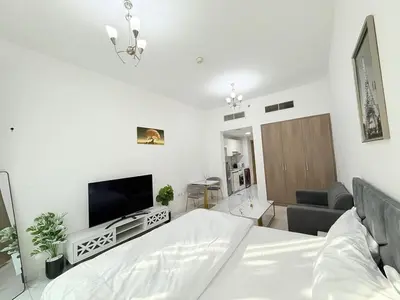 a white bedroom with a bed and a tv at A place like home in Dubai