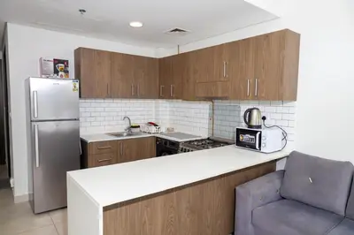 a kitchen with wooden cabinets and a refrigerator at Stunning Studio Apartment in Jvc in Dubai