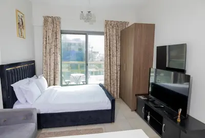a bedroom with a bed and a flat screen tv at Stunning Studio Apartment in Jvc in Dubai