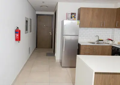 a kitchen with a stainless steel refrigerator and a hallway at Stunning Studio Apartment in Jvc in Dubai