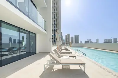 a row of lounge chairs on a building with a pool at Modern 2BR with Private Pool, Near Circle Mall And Quick Access from Al Khail Road, Binghatti Tulip, JVC by Deluxe Holiday Homes in Dubai