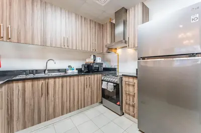 a kitchen with wooden cabinets and a stainless steel refrigerator at Walking distance to Dubai Mall and Burj Khalifa, Easy access to Dubai Metro and Top attractions, Dunya Tower, Downtown Dubai by Deluxe Holiday Homes in Dubai