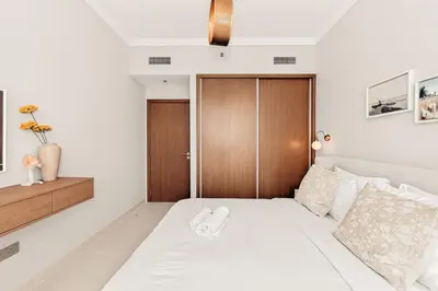 a bedroom with a white bed with a wooden door at Beachfront Luxury 2BR with Breathtaking Views in Dubai