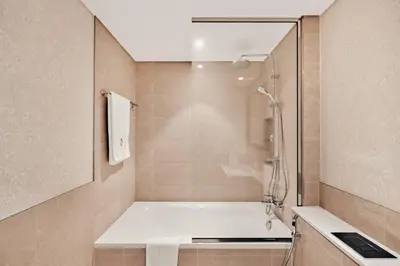 a bathroom with a shower and a white tub at Beachfront Luxury 2BR with Breathtaking Views in Dubai