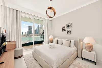 a white bedroom with a bed and a large window at Beachfront Luxury 2BR with Breathtaking Views in Dubai