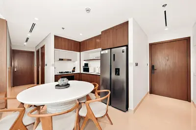 a kitchen with a white table and chairs and a refrigerator at Beachfront Luxury 2BR with Breathtaking Views in Dubai