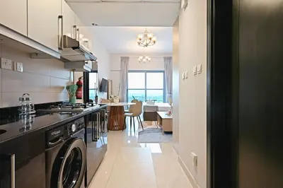a kitchen with a washer and dryer and a living room at Luxury Studio Near Downtown Dubai in Dubai