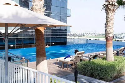 a woman sitting in a chair next to a swimming pool at BirdsEye Cozy Studio Mesmerizing Golf Views in Dubai