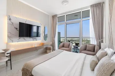 a bedroom with a bed and two chairs and a tv at BirdsEye Cozy Studio Mesmerizing Golf Views in Dubai
