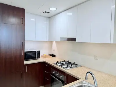 a kitchen with white cabinets and a stove and a microwave at Charming 1 BR with Balcony Retreat in Dubai