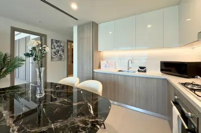 a kitchen with a glass table and white cabinets at Luxury 1-Bedroom Apartment with Full Marina View in Dubai