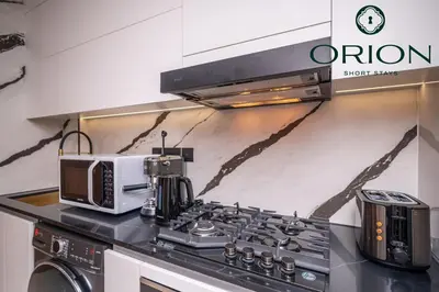 a kitchen with a stove top with a microwave at Stunning Luxury Studio with Jacuzzi and Canal View on High Floor, Close to Dubai Mall, Swimming Pool, Advanced Gym with PT, Sauna, Steam Room, Ice Bath, Swimming Pool, Best Building in Area in Dubai
