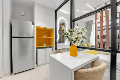 a kitchen with a white table and a refrigerator at Waves - Cozy & Modern JVC Escape With Pool & Gym Access in Dubai