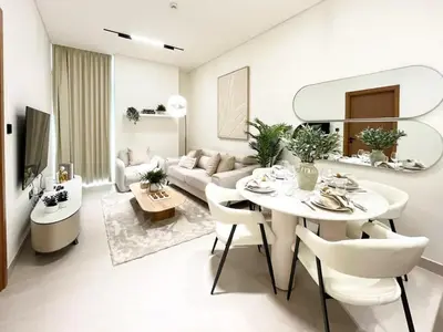 a white living room with a table and a couch at Serene Palette 1BR in Binghatti Azure with Gym & Pool in Dubai