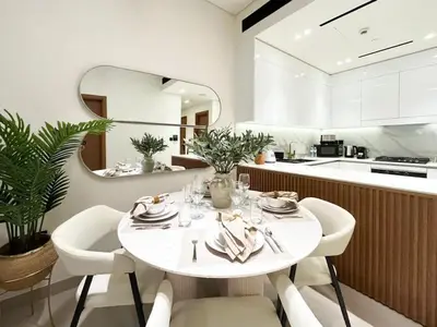 a white dining room with a table and chairs at Serene Palette 1BR in Binghatti Azure with Gym & Pool in Dubai