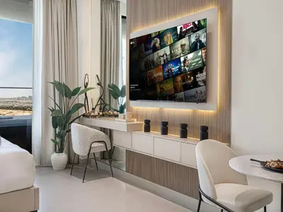 a living room with a tv and a table and chairs at Livin' Holidays - Studio - Bay View with Jacuzzi in Dubai