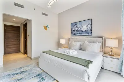 a white bedroom with a large bed and two lamps at Radiant - 3BR - JVC - near Sports City & Autodrome in Dubai