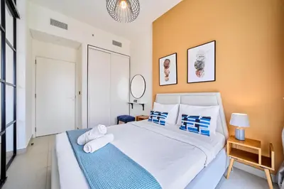 a bedroom with a large white bed with blue pillows at 1BR in Collective With Pool, Gym and CoWorking Space in Dubai