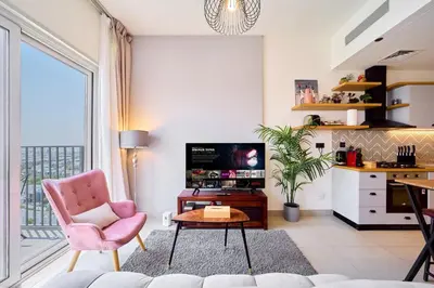 a living room with a pink chair and a tv at 1BR in Collective With Pool, Gym and CoWorking Space in Dubai