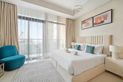 a bedroom with a large bed and a blue chair at Chic Studio in Dubai with Pool View Retreat Near Business Bay & Jumeirah Beach in Dubai