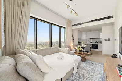 a living room with a couch and a large window at Stylish 2BR JVC with Pool, Gym Access, and City Skyline Views in Dubai