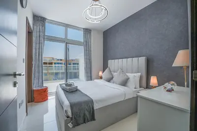 a bedroom with a bed and a large window at EasyGo Spacious 3BR with Garden in DAMAC Hills 2 in ‘Ūd al Bayḑāʼ