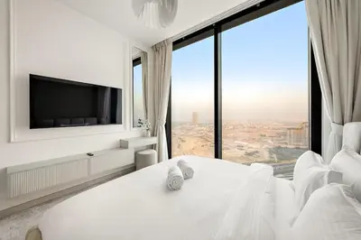a bedroom with a large white bed with a large window at FIRST CLASS 4BR Sobha Skyline Luxury in Dubai