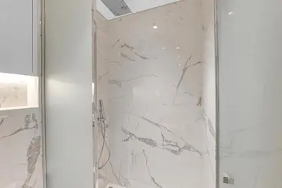 a shower with marble walls and a glass door at Chic Dubai Retreat at Azizi Riviera 65 in Dubai