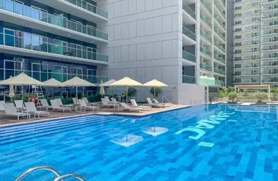 a large swimming pool with chairs and a building at Cosy 2BR Business Bay with Canal view and Swimming pool in Dubai